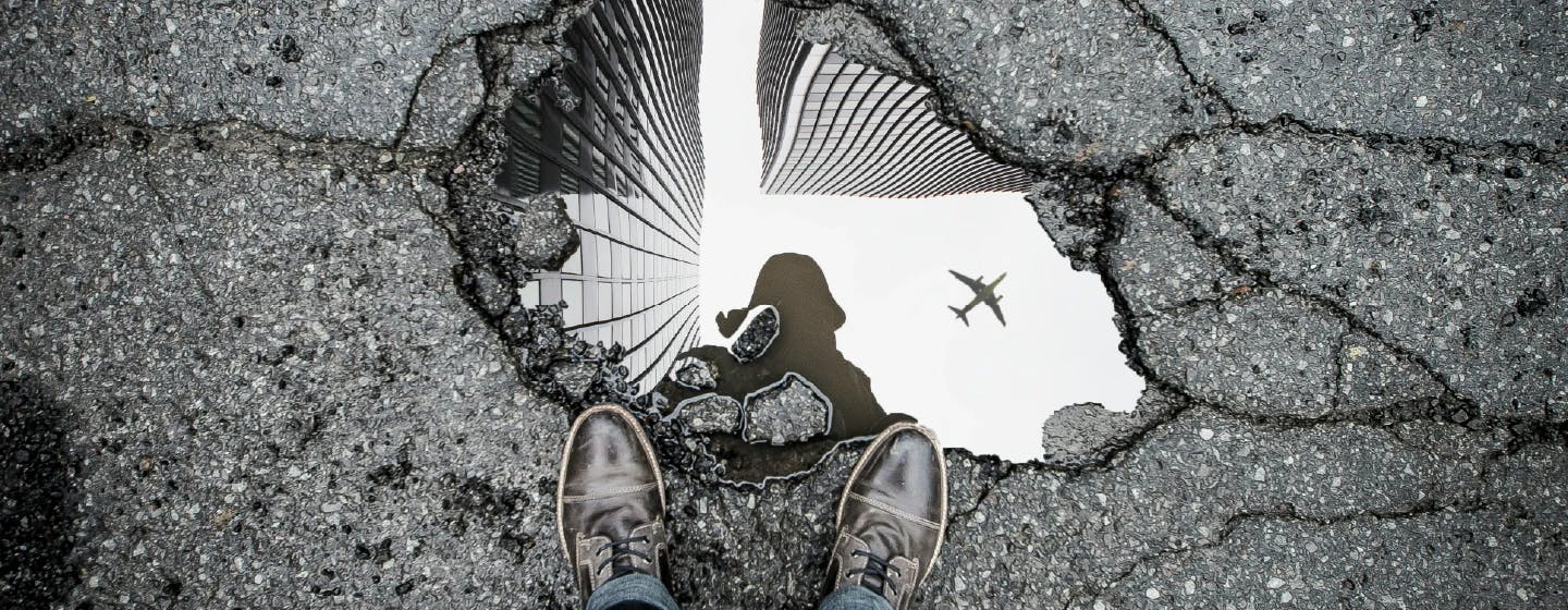 a pothole filled with water reflecting a plane in the sky representing a way out